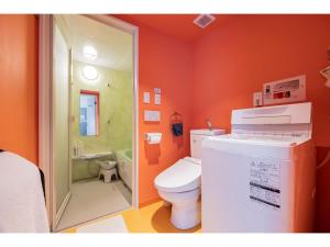 y baño de color naranja con aseo y ducha. en bmj Shinjuku Okubo - Vacation STAY 68278v, en Tokio