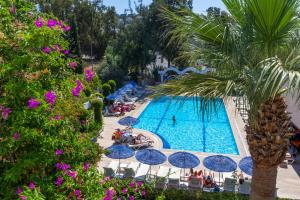 ein Schwimmbecken mit Sonnenschirmen und Menschen, die darum herum sitzen in der Unterkunft Natur Garden Hotel in Bitez