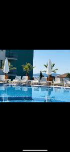 a large swimming pool with white chairs and umbrellas at Gardenia Vacation Settlement in Sozopol