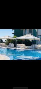 a swimming pool with an umbrella and some chairs at Gardenia Vacation Settlement in Sozopol