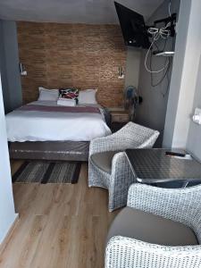 a bedroom with a bed and two wicker chairs at Busis guesthouse in Durban