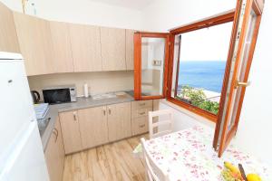 kuchnia z dużym oknem i stołem z tabelą sidx sidx w obiekcie Seaside Apartments Hrkać w Orebiciu