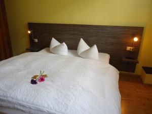 a white bed with a bouquet of flowers on it at Stadthotel Regensburg in Regensburg