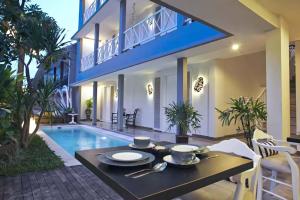 una mesa de comedor frente a una casa con piscina en The Kanjeng Suites Petitenget, en Seminyak 3 fotos más