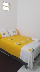 Una cama con una manta amarilla con flores. en Residência dos Félix, en Morro de São Paulo