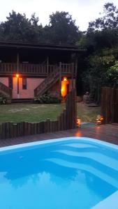 a large blue swimming pool in front of a house at Quinta do Urutau in Praia do Rosa