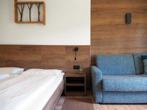 a bedroom with a bed and a blue chair at Pension Rungg in Badia