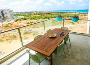 una mesa de madera en un balcón con vistas al océano en פנינה באכזיב- מול הים- achzivacation en Nahariyya