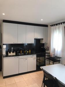 a kitchen with white cabinets and a black counter top at Appartamento da 2 locali a Bosco Gurin in Bosco Gurin