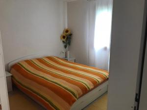 un letto in una stanza con un vaso di fiori di Appartamento da 2 locali a Bosco Gurin a Bosco Gurin