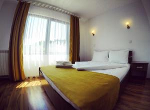 a bedroom with a large bed with a large window at Vila Simina in Vatra Dornei