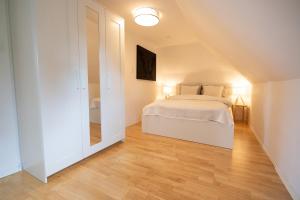 a bedroom with a white bed and a wooden floor at Apartment 27 in Coburg