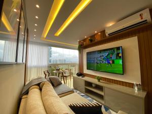 uma sala de estar com um sofá e uma televisão de ecrã plano em Itaparica LUXO & DESIGN 24 HORAS em Vila Velha