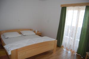 Apartments Organic tourist farm Jeglijenk في Šentjanž pri Dravogradu: غرفة نوم بسرير وستارة خضراء