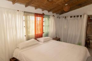 1 dormitorio con 1 cama con sábanas blancas y ventanas en Ideal y linda casita en San Cristóbal-Galápagos, en San Cristobal