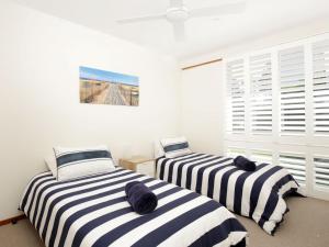 two beds in a room with white walls and windows at Beach Street Residence Huskisson in Huskisson