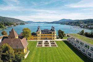 an aerial view of a large building on a lawn with a lake at Evita Wörthersee in Krumpendorf am Wörthersee