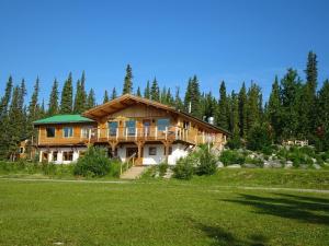 a large wooden house with a green roof at Southern Lakes Resort in Tagish