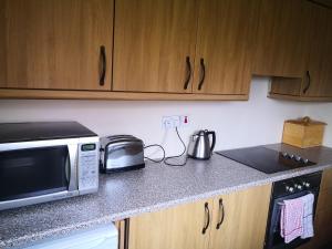 a kitchen counter with a microwave and a toaster oven at Cloughey Beach House in Kircubbin