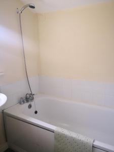 a white bath tub with a shower in a bathroom at Cloughey Beach House in Kircubbin +10 photos
