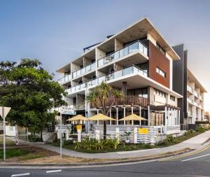 レッドクリフにあるThe Sebel Brisbane Margate Beachの通りに傘を置いたアパートメントビル