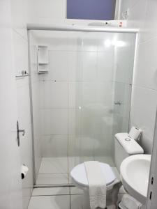 a white bathroom with a shower and a toilet at Hotel Apiai in Apiaí