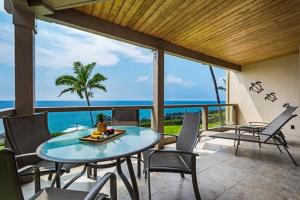 un patio con mesa, sillas y el océano en Keauhou Kona Surf and Racquet Club 2-204 en Kailua-Kona