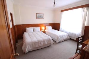 a hotel room with two beds and a window at CHALET CHAPITAL Punta Arenas in Punta Arenas