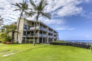 duży budynek z palmami przed oceanem w obiekcie Keauhou Kona Surf & Racquet Club #5-104 w mieście Kailua-Kona