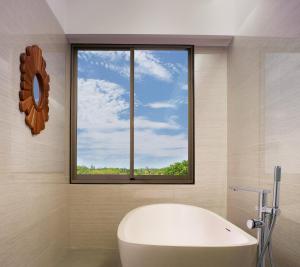a bathroom with a bath tub and a window at MERUSAKA Nusa Dua in Nusa Dua