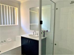 uma casa de banho com um lavatório e um chuveiro em Entire 4BR House close to Airport Hosted by Homestayz em Gladstone