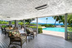 an outdoor deck with chairs and a table and a pool at Hale Pahukoa in Kailua-Kona
