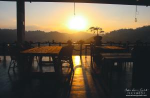 a sunset with tables and chairs on a patio at Square Peg in Kandy