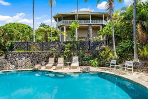 a swimming pool with chairs and a house at Ono Hale in Kailua-Kona