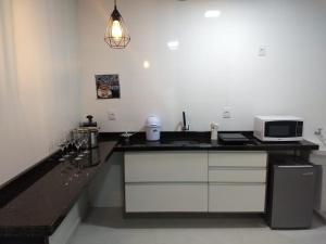 a kitchen with a black counter top and a microwave at Flat Santa Cruz do Sul in Santa Cruz do Sul +8 photos
