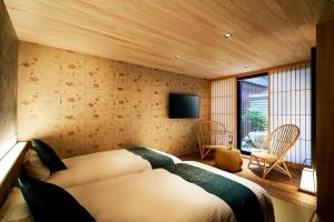 a bedroom with two beds and a tv on the wall at Kikokutei Bekkan in Kyoto