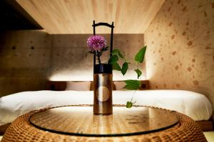 a vase with a flower on a table in a bedroom at Kikokutei Bekkan in Kyoto