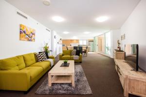 a living room with a yellow couch and a table at Lanai Riverside Apartments in Mackay