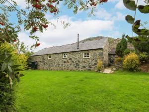 an old stone house with a green lawn at Nant Bach in Pwllheli