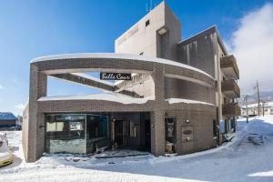 a building with a sign on it in the snow at Hotel Belle-Cour Inomata in Otari