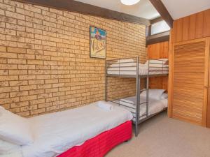Zimmer mit 2 Etagenbetten und Ziegelwand in der Unterkunft Clearview 2 8 Bogong Street in Jindabyne
