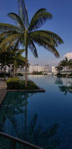 a swimming pool with palm trees and buildings in the background at Cosy Studio Netflix SelfCheckIn Cyberjaya 3 in Cyberjaya