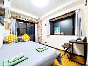 a bedroom with a bed and a desk and a window at nestay suite tokyo tabata in Tokyo