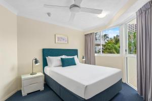 a bedroom with a white bed and a window at Surf Parade Resort in Gold Coast