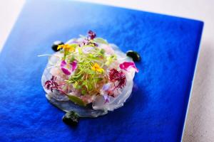 a dish with flowers on a blue plate at Aubergeフレンチの森 in Kusumoto