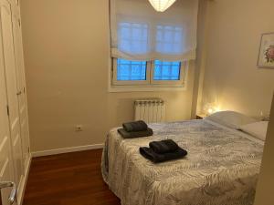 a bedroom with a bed with two black towels on it at Churruca Center 2 hab in Vigo