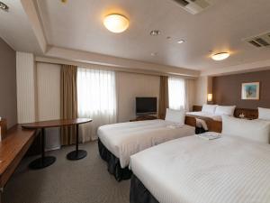 a hotel room with two beds and a television at Alpico Plaza Hotel in Matsumoto