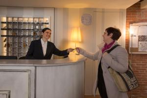 Un homme et une femme serrent la main dans un bar dans l'établissement Hotel Alma Domus, à Sienne