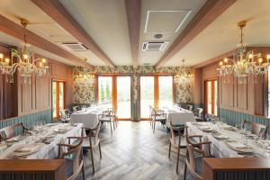 a dining room with tables and chairs and chandeliers at Aubergeフレンチの森 in Kusumoto