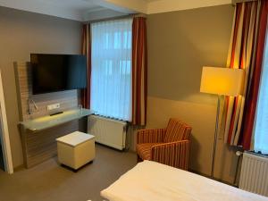 a hotel room with a bed and a tv and a chair at Hotel Goldene Krone in Goslar